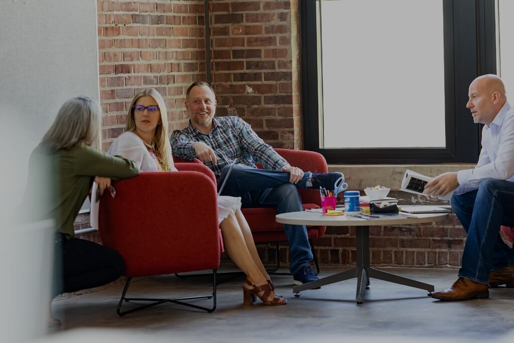 Four coworkers sitting around a low table in a corner, having a conversation