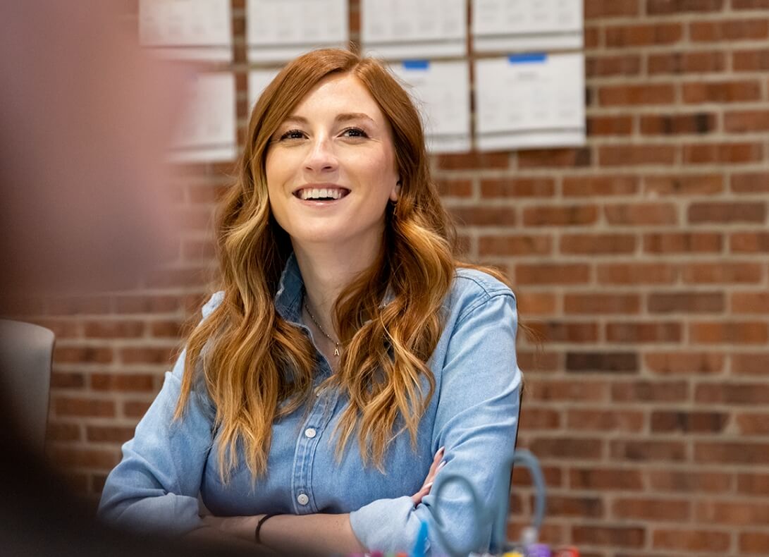 Over-the-shoulder view of a woman sitting at a table and smiling