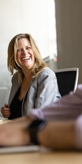 Over-the-shoulder view of a woman sitting at a table and smiling